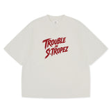 Trouble in St. Tropez Tee unisex cotton t-shirt in off-white by Creo Studios